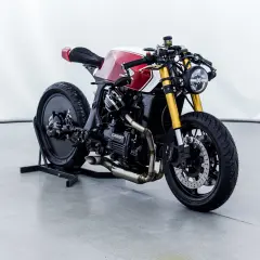 Honda CX650 custom cafe racer, rossa e bianca, con forcella dorata e scarico modificato. Un vero gioiello su due ruote.