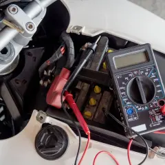 Controllo batteria scooter con multimetro. Si sta per caricare la batteria dello scooter in casa, verificando la tensione con un tester.