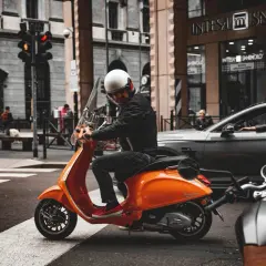 Uomo su scooter 150 con patente B, fermo al semaforo in città.