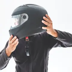 Persona indossa un casco nero, mostrando le sue parti. Le mani regolano il cinturino e la visiera.