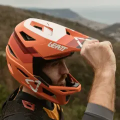 Uomo con casco integrale Leatt arancione, pronto per downhill. Il casco integrale significato è protezione totale.