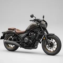 Moto custom bobber marrone con sella in pelle, cerchi color bronzo e faro tondo. Stile minimalista e aggressivo.