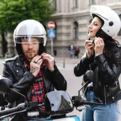 Coppia in moto, lui sistema il suo casco nuovo che fa male, lei il suo.