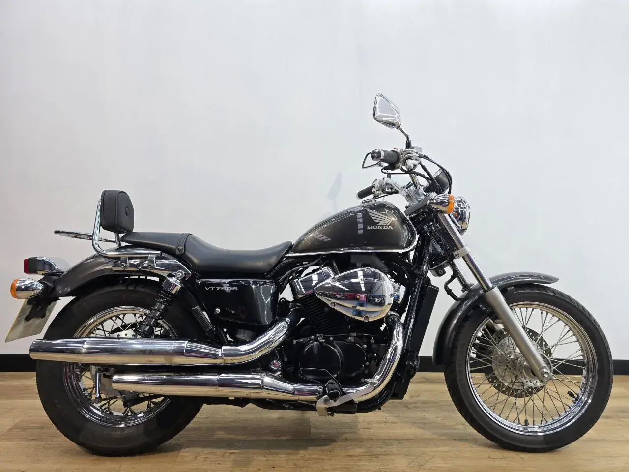 Honda VT750S cromata e scura, con sella nera e schienalino per il passeggero.