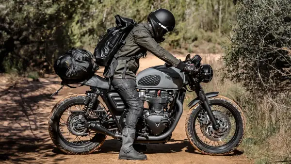 Motociclista con zaino e borse moto custom, pronto per un'avventura su sterrato.